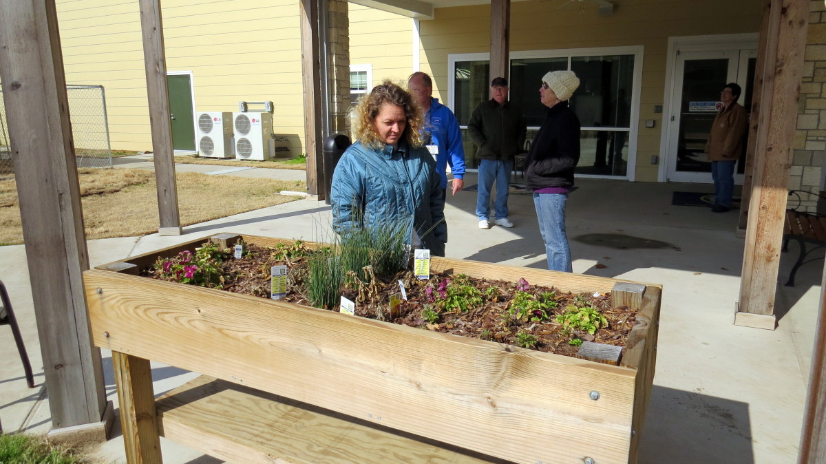 BIS President Karen Woods inspects a flower box in the courtyard.